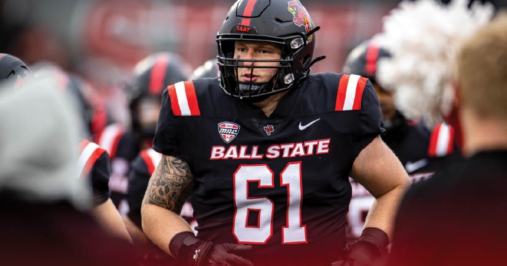 Luke Dalton runs on the field in his Ball State football uniform and helmet. The background is blurry and in motion.