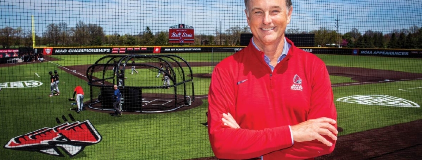 Mike Shebek stands in front of the Shebek Stadium with his arms crossed in a red Ball State pullover.