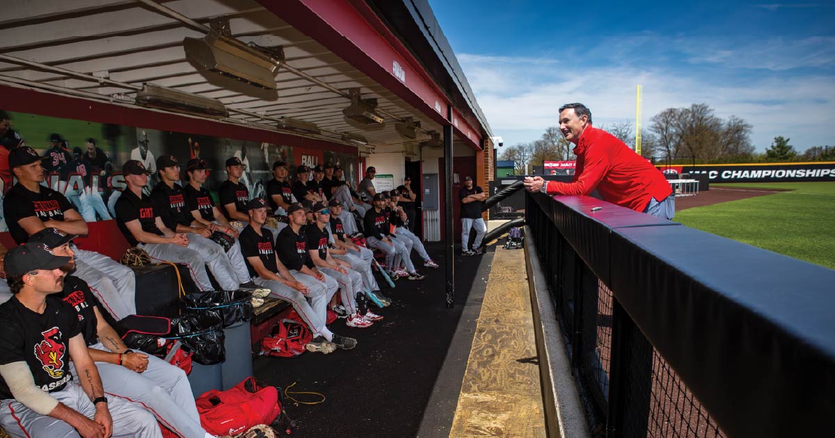 Mike Shebek speaks to the Ball State baseball team sitting in the dugout.