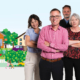 Four adults pose confidently with arms crossed in front of illustrated houses, trees, and a lively community scene