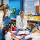 Teachers assist young Burris students with classroom activities around a table in a classroom.