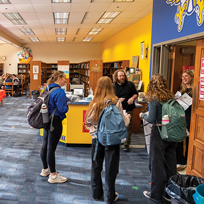 Burris students talk to staff at a counter in the school library.