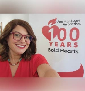 Molly A. McGuire stands in front of an event poster smiling.