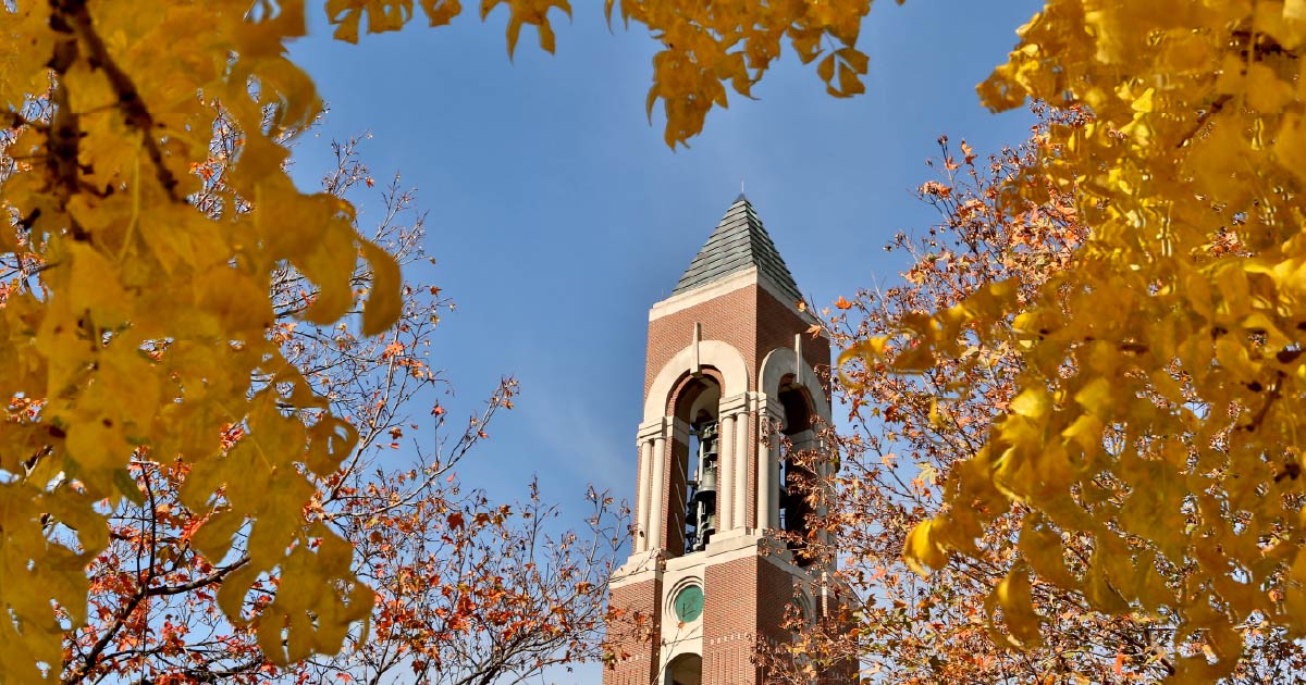 Bell Tower framed by fall trees with a blue sky in the background.