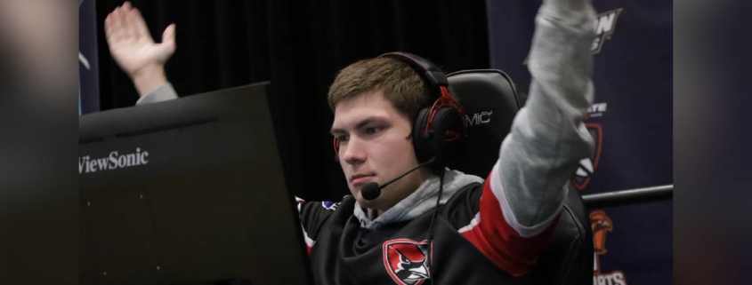all State student wearing a headset raises arms in celebration while competing in an esports match.