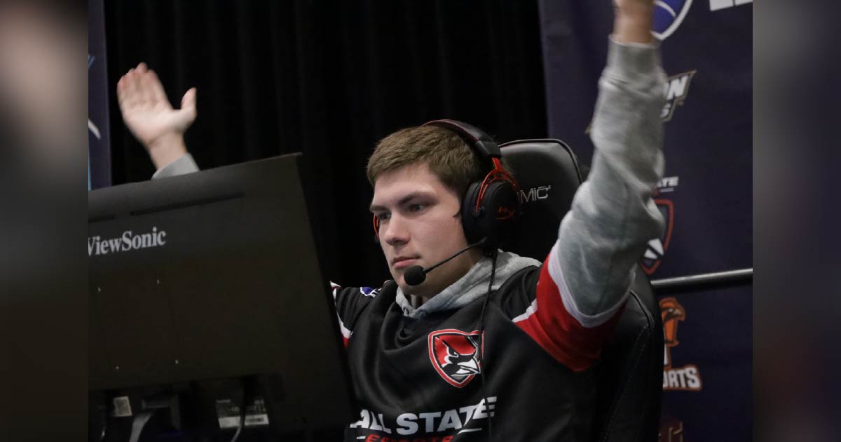all State student wearing a headset raises arms in celebration while competing in an esports match.