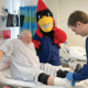 Person on bed with ankle wrapped, Charlie cardinal in background and nursing student tending to ankle