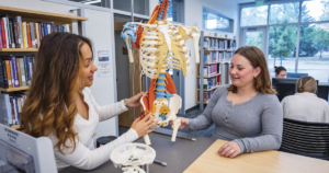 two female students in the library looking at a skeleton
