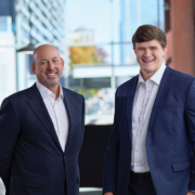 Lou Hensley (left) and Caleb Murray (right), both smiling and dressed in suits.
