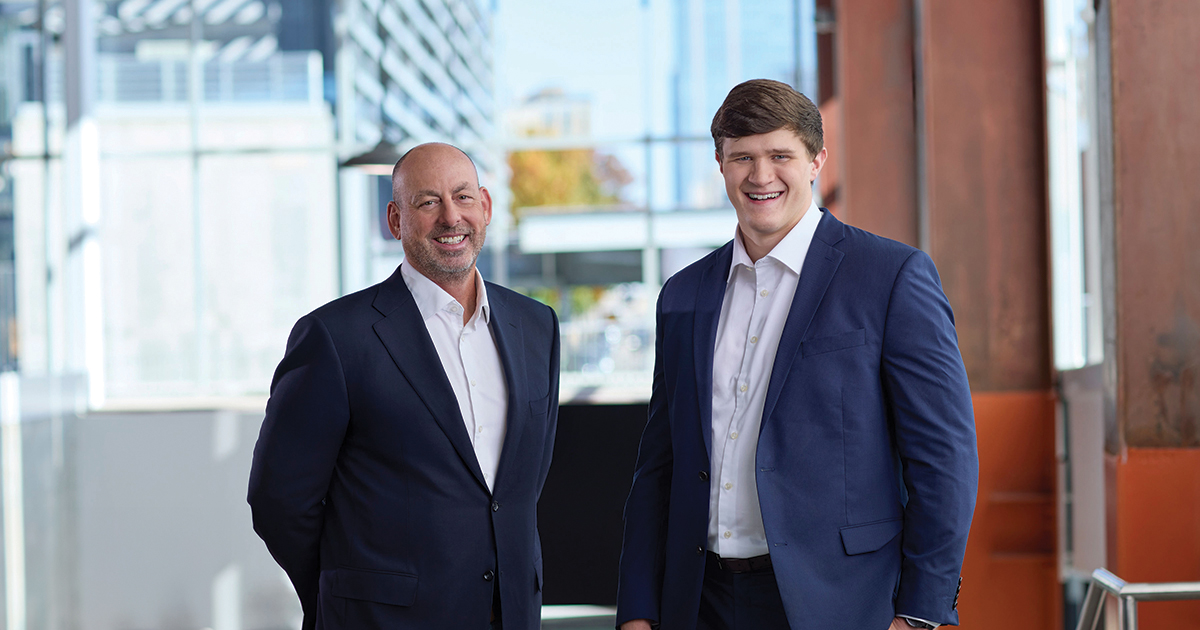 Lou Hensley (left) and Caleb Murray (right), both smiling and dressed in suits.