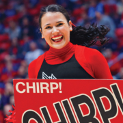 A Ball State cheerleader smiles while holding a sign that reads "Chirp! Chirp!"
