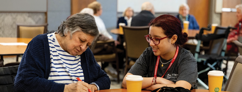 Woman with student writing at a table