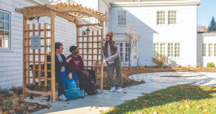 People sitting on a bench in front of a white house