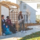 People sitting on a bench in front of a white house
