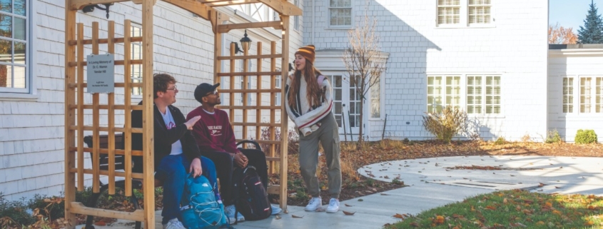 People sitting on a bench in front of a white house