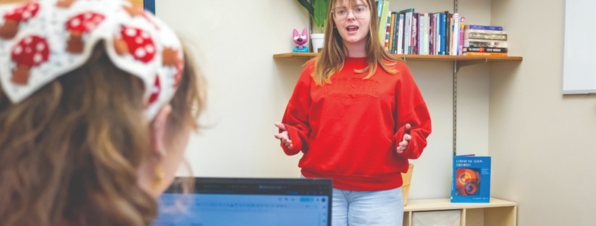 Woman speaking with her hands to a woman on a laptop