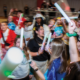 A road of young adults dance with glow sticks.