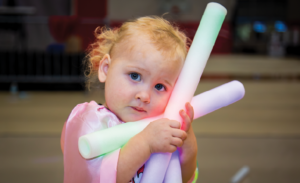A child holds glow sticks and looks into the camera.