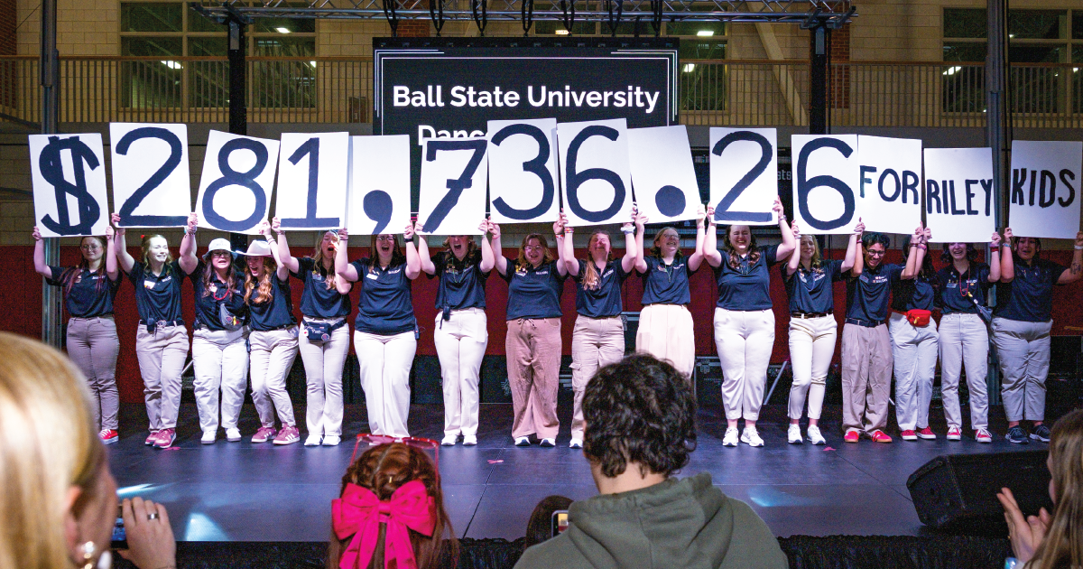 Students hold up signs that list thee amount of money raised at the dance marathon. 