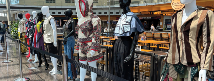 Mannequins lined up at the airport wearing handmade garments.