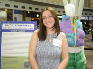 A woman poses in from of a vest she made.