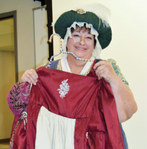 A woman holds up a red dress.