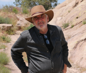 Man stands outside with a tan cowboy hat on.