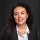 A portrait of a woman in a blazer against a black background
