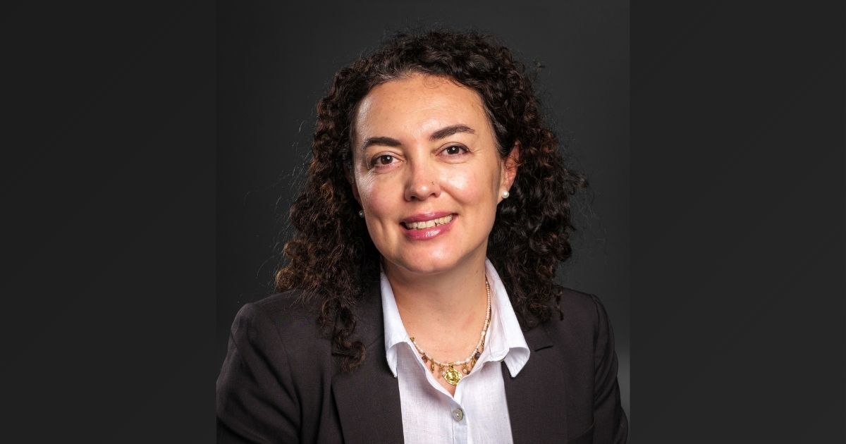 A portrait of a woman in a blazer against a black background