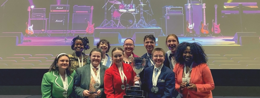 A group of people pose for a photo while holding an award