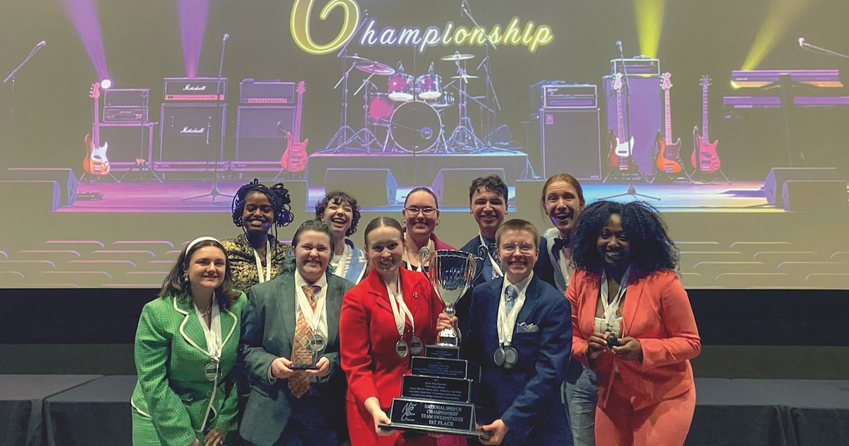 A group of people pose for a photo while holding an award