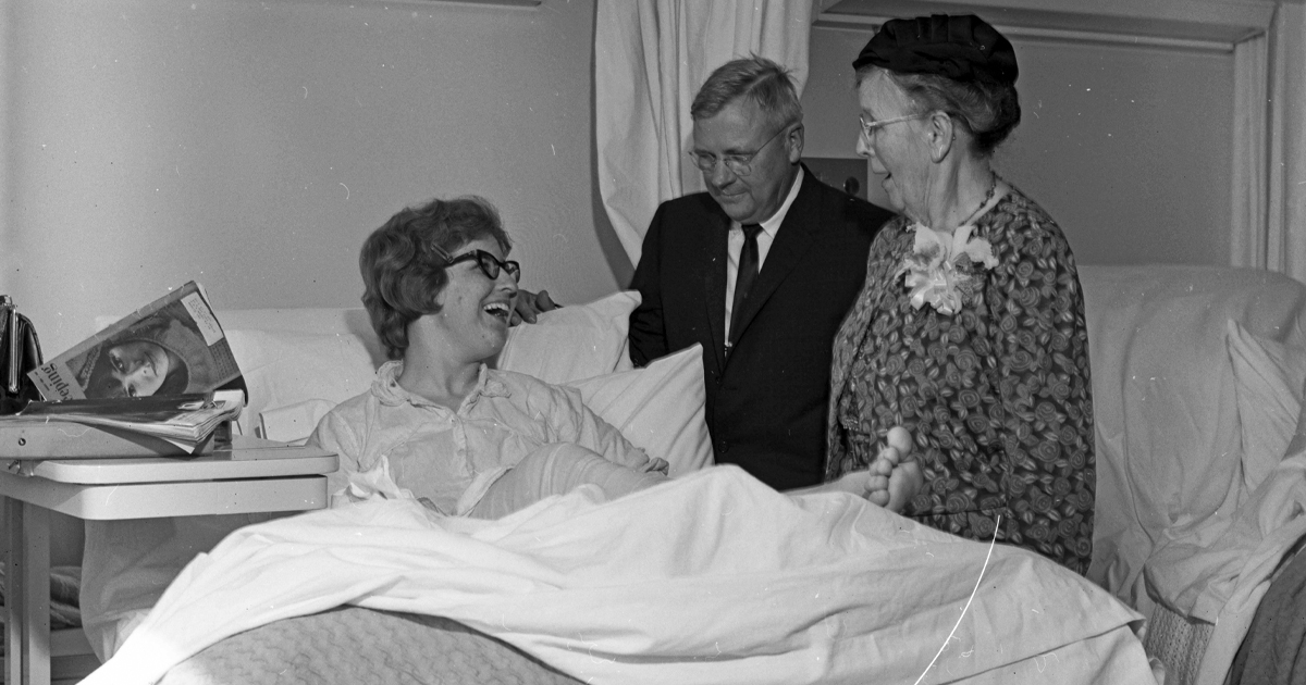 Two doctors standing at the bedside of a patient. Black and white photo