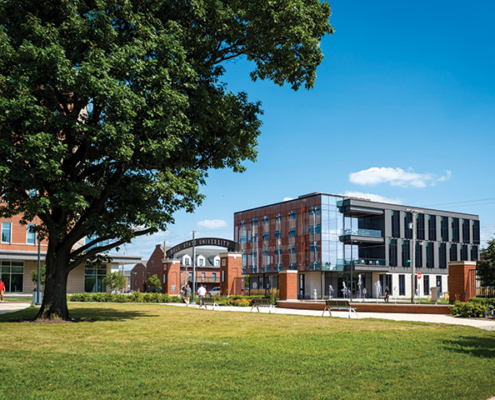 Exterior of the Center for Innovation and Collaboration at Ball State University, seen across a lawn with a large tree in the foreground.