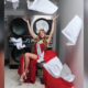 A woman sits in front of her laundromat in a red dress.